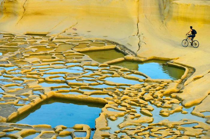 A cyclist takes a break at the ancient salt pans of Gozo.