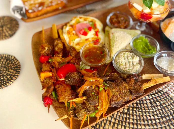 A selection of meat skewers arranged on platters alongside various dips and breads.