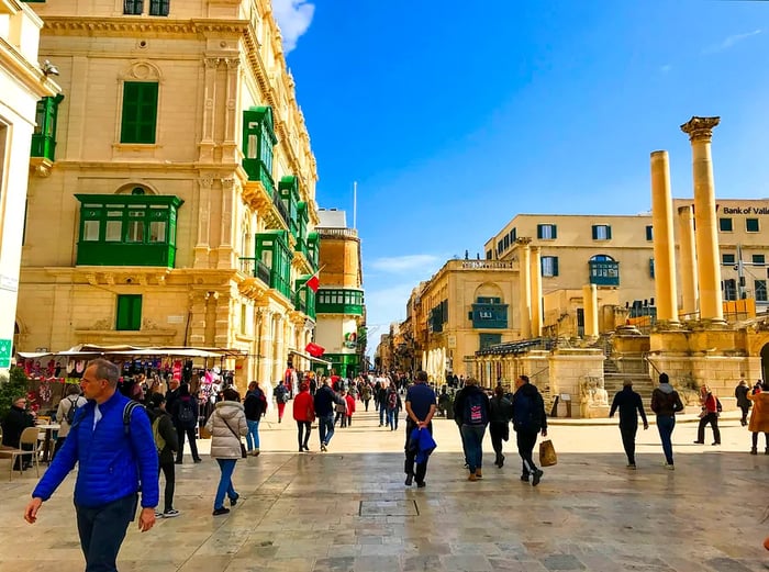 Visitors stroll through the historic heart of Valletta on a bright morning.