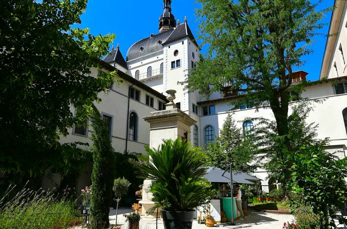 A guest places an order at a bar nestled among trees in the inner courtyard of the former hospital Hotel-Dieu in Lyon.