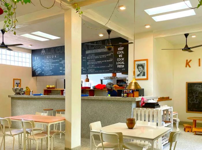 A bright and spacious café interior adorned with white paint, featuring a chalkboard menu above the counter.