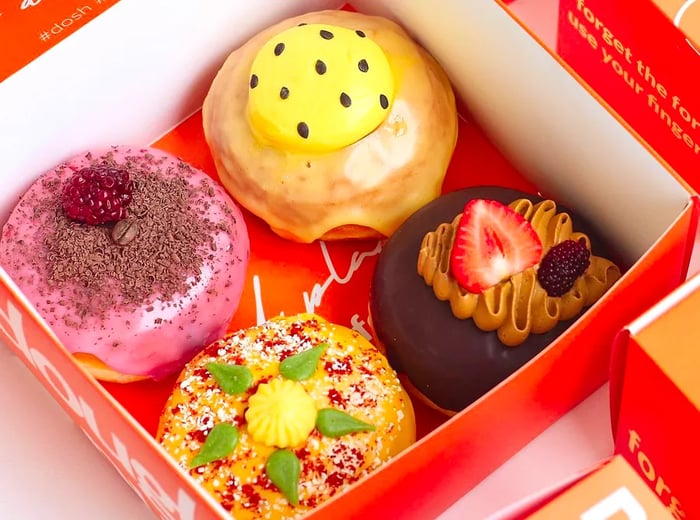 A box containing four whimsically decorated doughnuts.