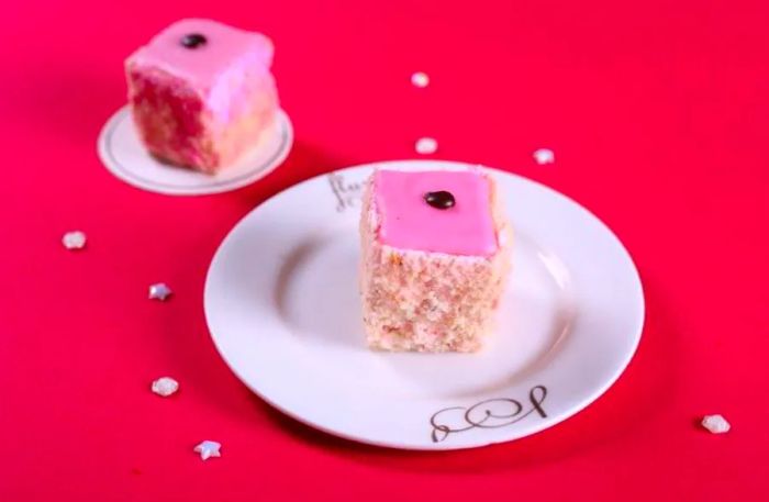 A delightful cube of cake adorned with pink icing.