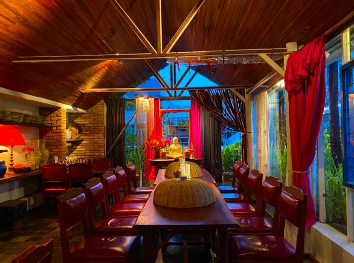 A long table sits in a wood-paneled A-frame setting, with a golden Buddha statue displayed at the far end.