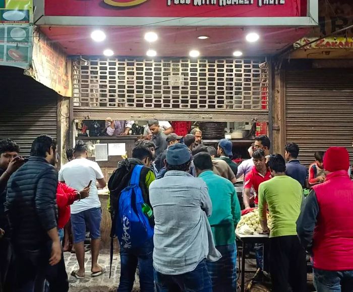 A bustling crowd gathers outside a popular restaurant at night.