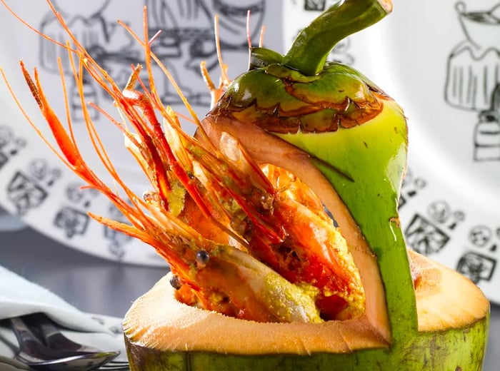 Prawns spill from a coconut shell, accompanied by decorative plates on display.