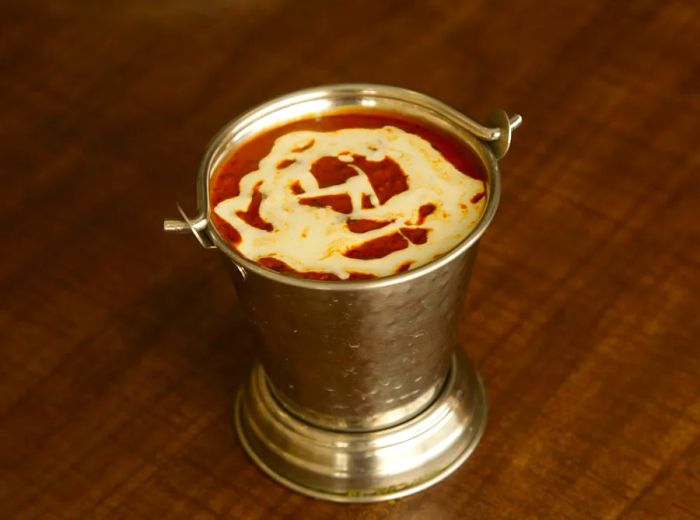 A small metal tin filled with dal makhani, beautifully garnished with a swirl of cream.