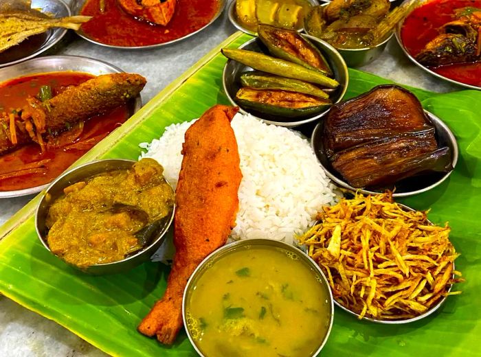 A spread of fish and side dishes laid out on a table, with some served on a large leaf.