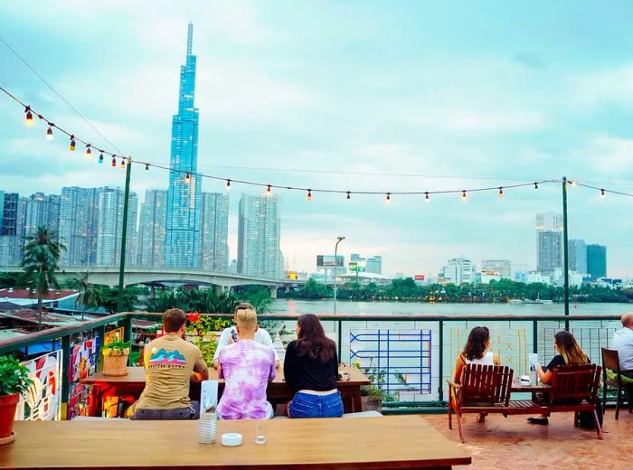 Patrons relax at tables and adirondack chairs, soaking in stunning views of the city skyline.