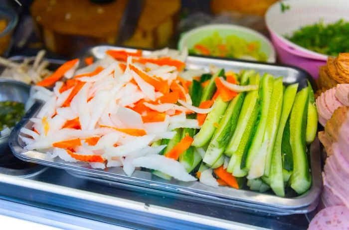 Stacks of fresh vegetables arranged in a metal prep tray.