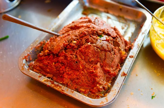 A serving tray filled with a mound of pate and a spoon resting on top.