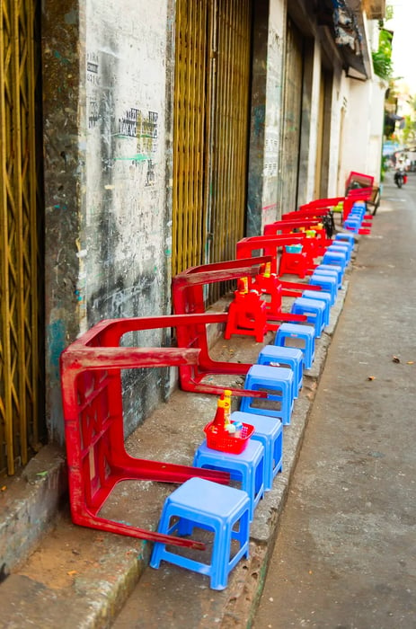 Upside-down plastic tables and low stools lining an empty street.