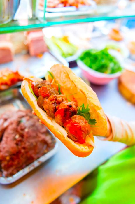 A banh mi piled high with succulent pork patties, drenched in sauce.