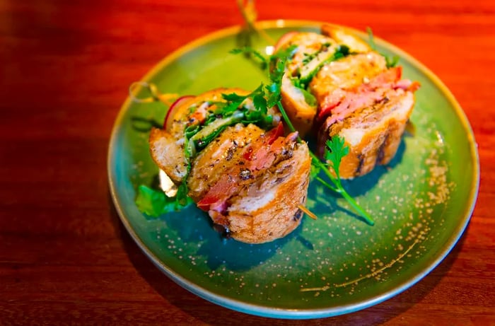 Slices of bánh mì arranged on a ceramic green plate.