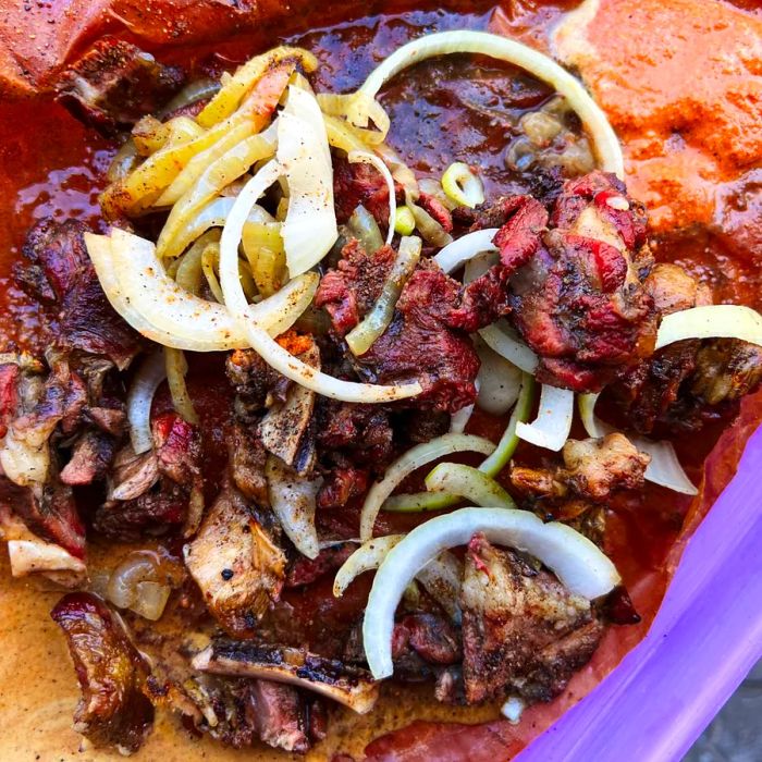 From above, a vibrant display of chopped grilled meat, crowned with onions and accompanied by dollops of various sauces.