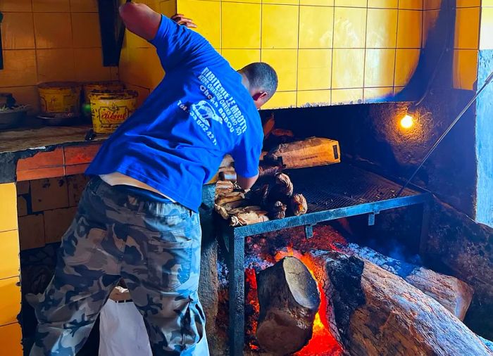 A chef leans into a blazing hearth.