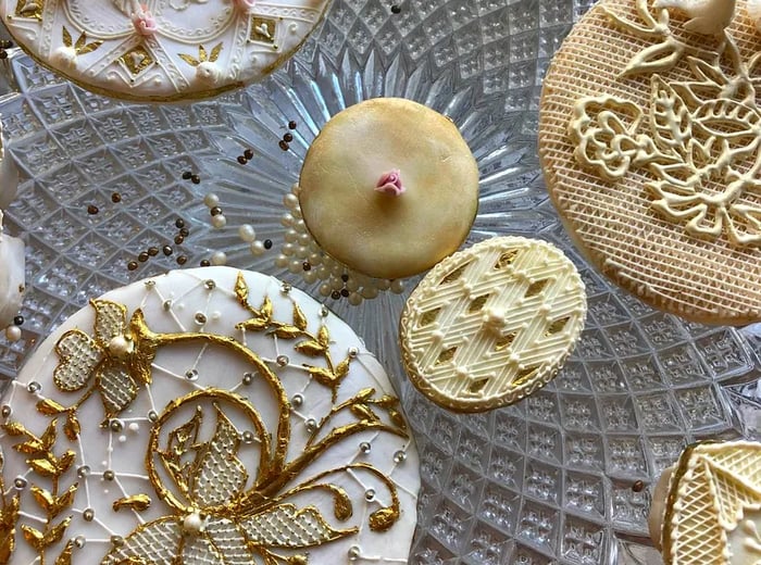 Delicately iced and decorated cookies arranged on a glass plate.