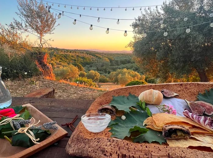 A selection of appetizers on a low table, set against a breathtaking dusk landscape.