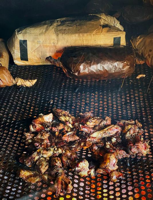 Chopped meat displayed in the front section of the grill, with kraft paper packages situated at the back.