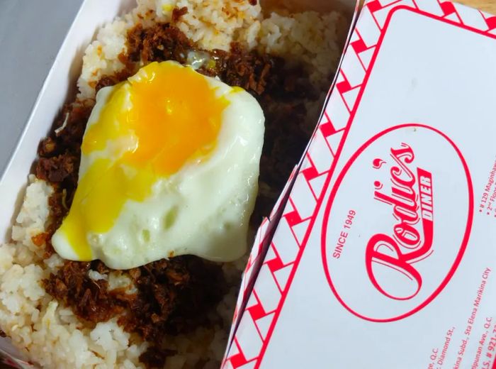 A view from above of tapsilog in a takeout container, showcasing the top of the branded box.