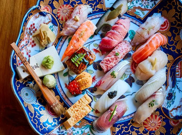 Aerial view of exquisitely arranged sushi pieces on an ornate platter.