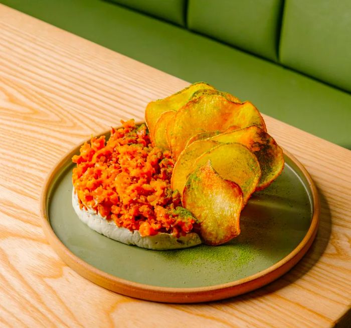 A crescent of vivid orange tartare, accompanied by large, wavy potato chips.