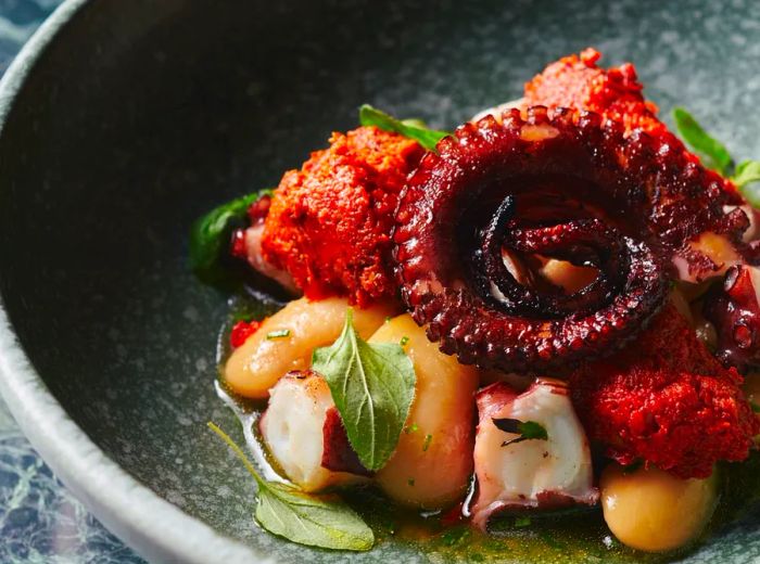 A swirl of octopus resting atop a medley of roasted vegetables.