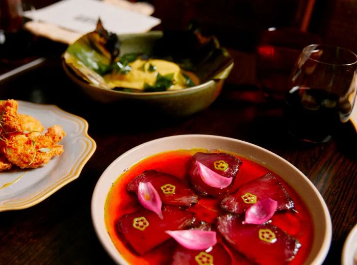 A selection of vibrant dishes, including slices of sashimi drizzled with a rich red sauce.