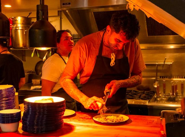 A chef delicately grates cheese onto a dish in a cozy, softly lit kitchen.