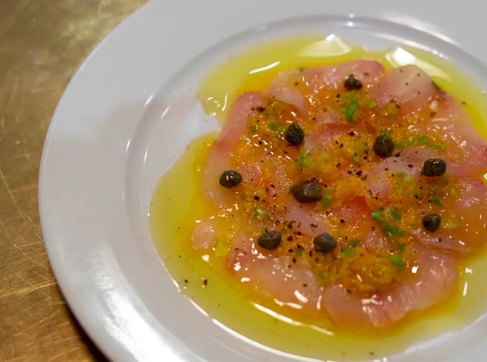 Delicately sliced crudo resting in a pool of oil.