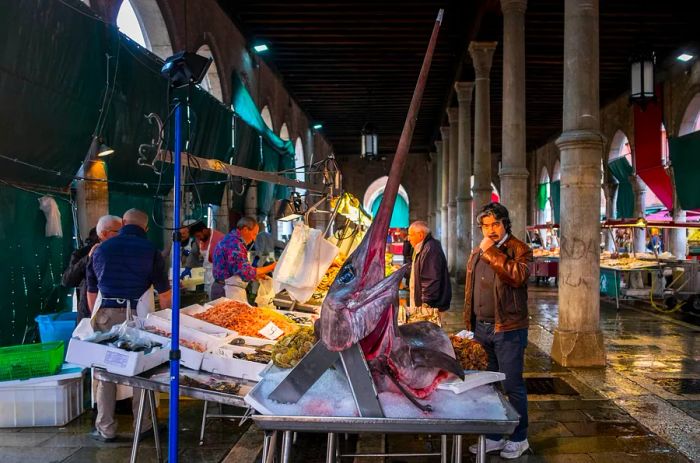 Fishmongers display an array of fresh seafood, including enormous swordfish, at the Rialto fish market in Venice, Italy.