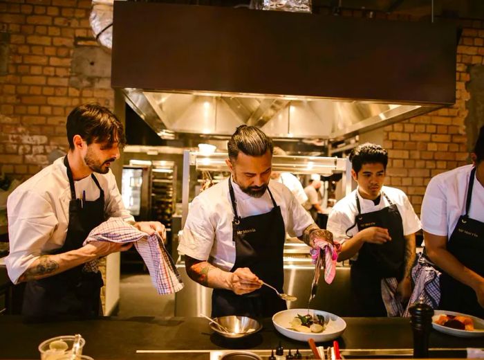 A chef and kitchen staff preparing meals in an open kitchen setting.