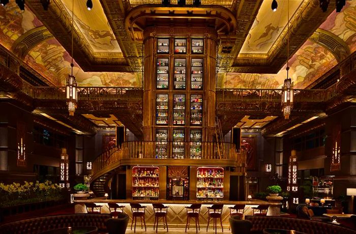 A striking tower of shelves brimming with bottles in the heart of an opulent, dimly lit room.