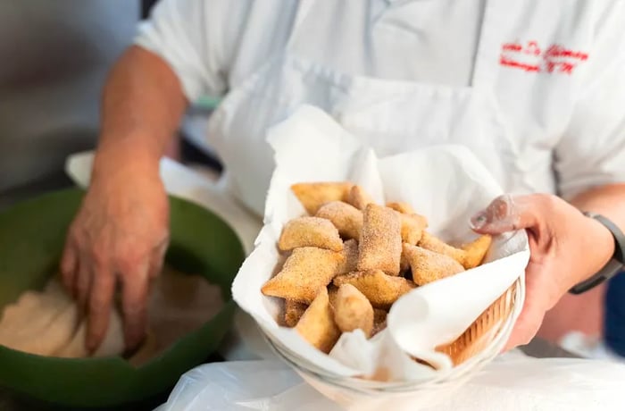 A chef presents a basket brimming with sopaipillas.