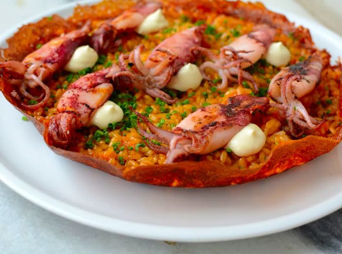 A serving of small squid presented on a rice dish within a large shell.