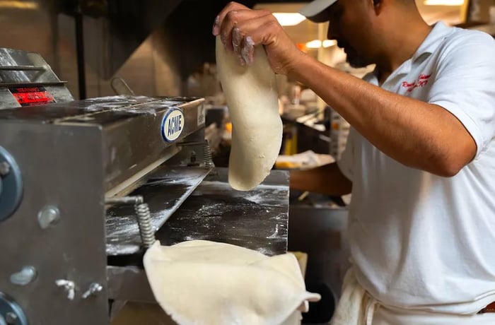 A chef presents a flattened disc of dough.