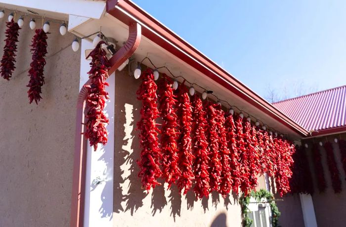 The bright exterior of a building adorned with strings of hanging chiles. 