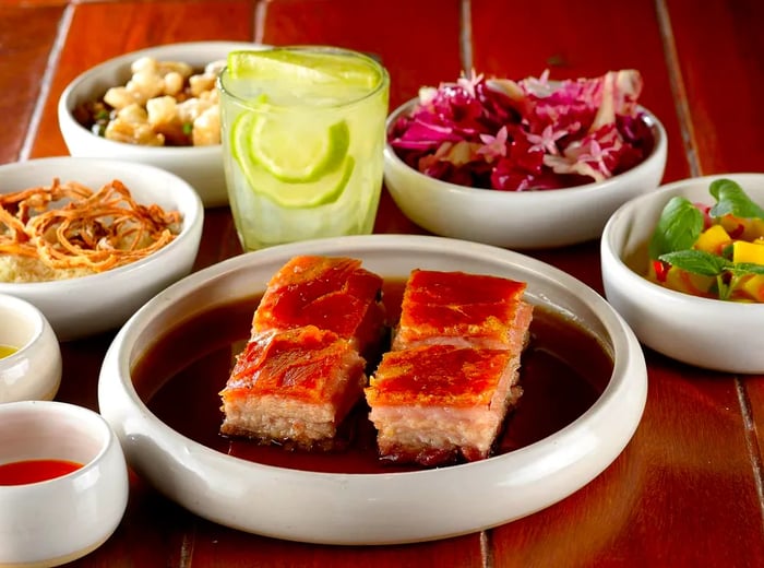 A platter featuring four substantial portions of roasted pork, accompanied by salads and beverages.