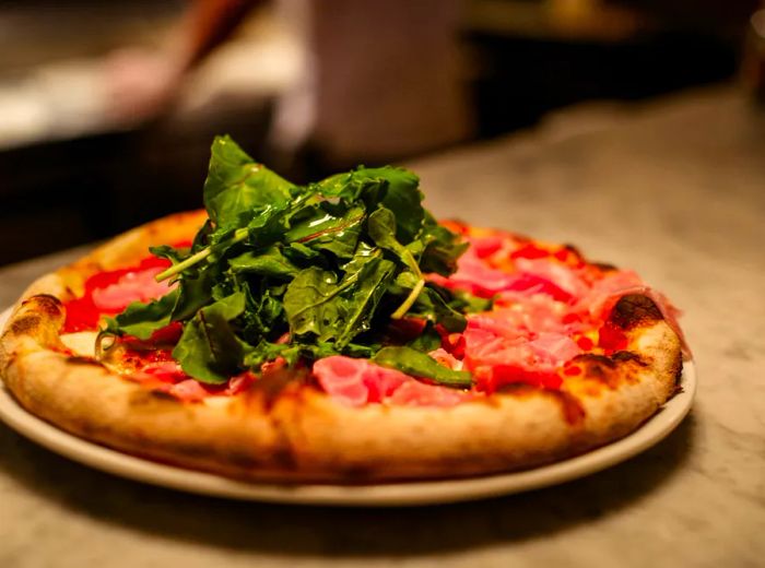 A beautifully arranged pizza topped with a generous amount of fresh greens.