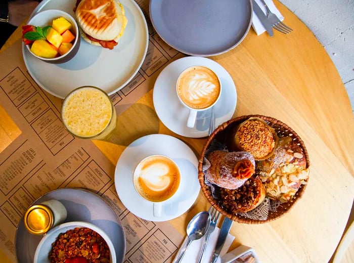 An aerial view of a table filled with pastries, sandwiches, and coffee.