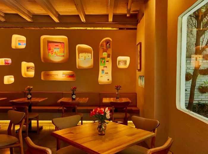 An interior featuring vibrant backlit art displays, dining tables, and a view into a charming courtyard.