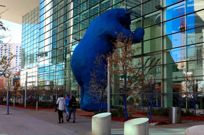 A massive sculpture of a blue bear peering into a building in Denver