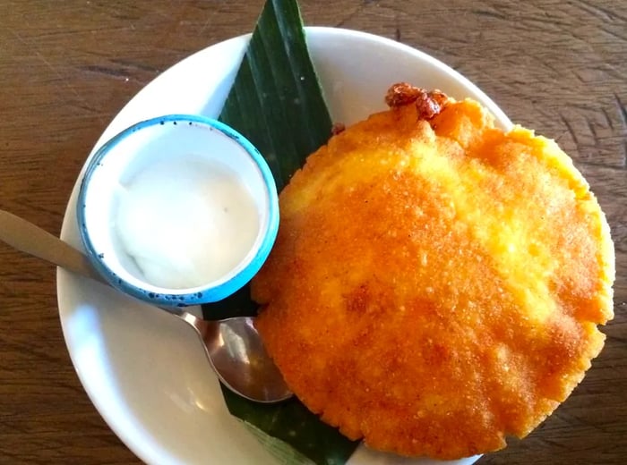 A close-up shot of a large arepa accompanied by a small container of sauce.