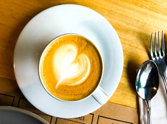 An overhead view of two lattes adorned with artistic milk foam designs.