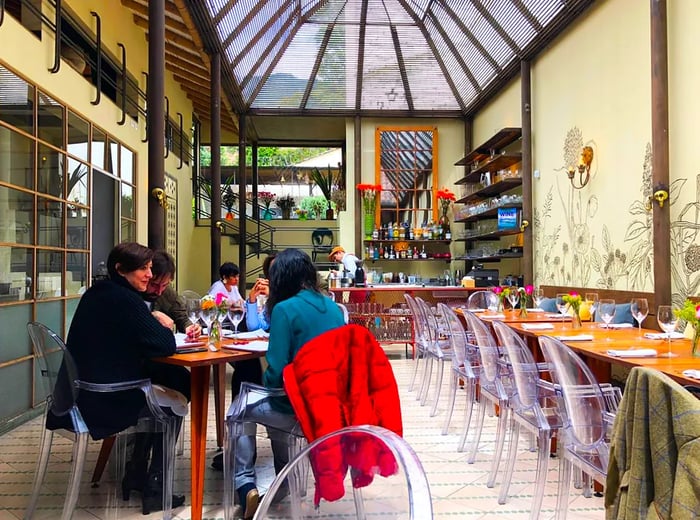 Patrons dining under a spacious glass ceiling in a bright environment.