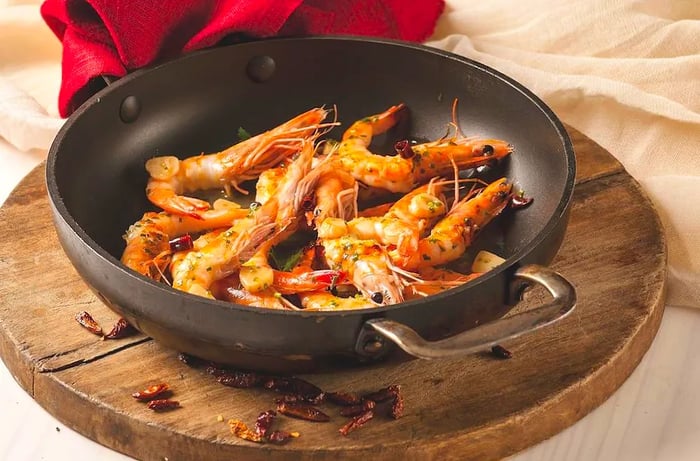 A large skillet filled with shrimp.