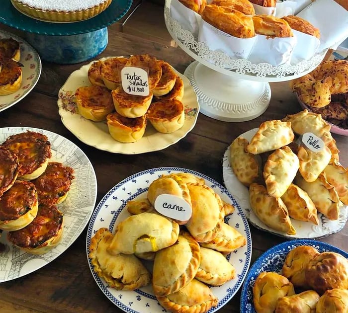 A variety of empanadas and baked treats adorned with small labels for identification.