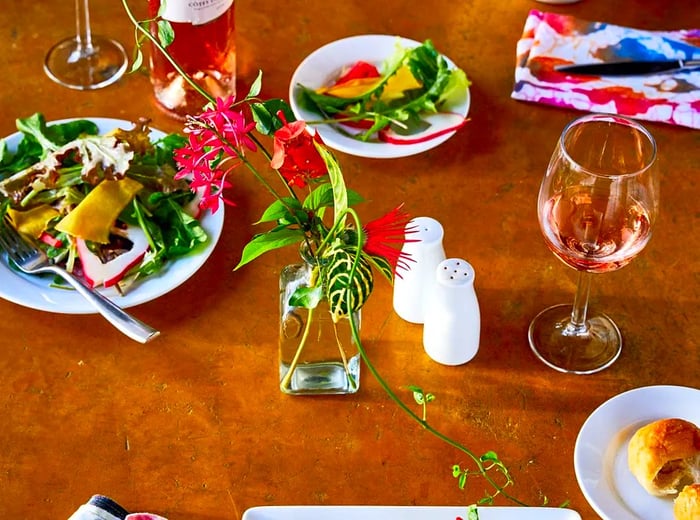 A wooden table adorned with flowers, salt and pepper shakers, and an array of salads.