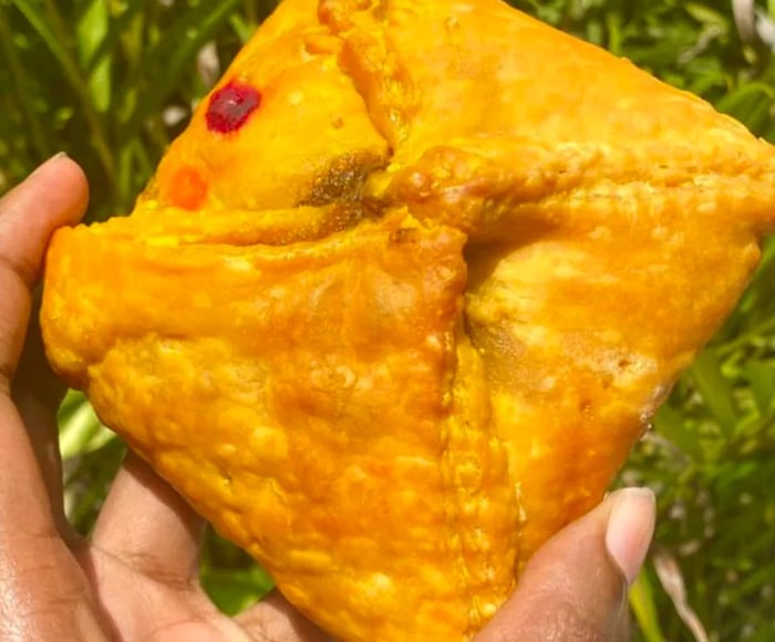 A hand holds a golden fried patty.