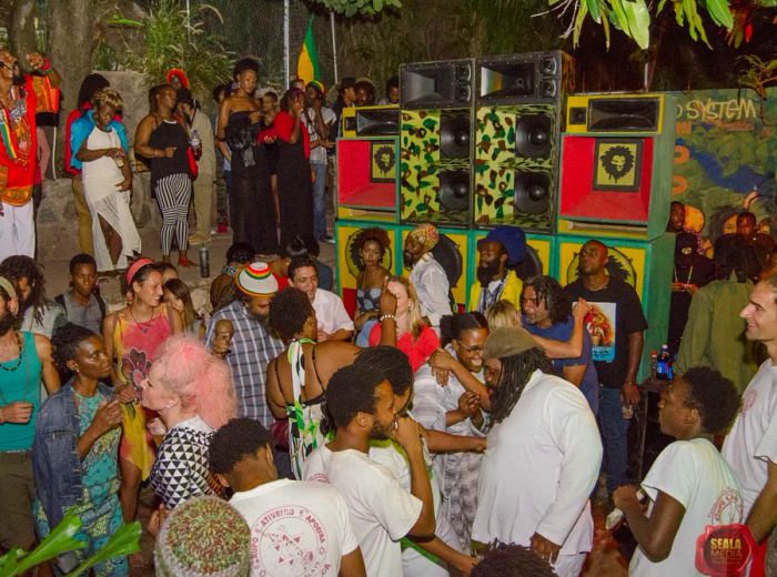 A lively crowd dancing in front of vibrant speakers.